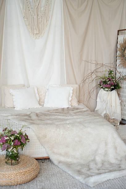 istock cozy and serene bohemian bedroom featuring a fluffy fur throw draped over a bed with white and beige pillows, adorned with woven art and floral arrangements in a tranquil setting, ethereal, simple 2226255985