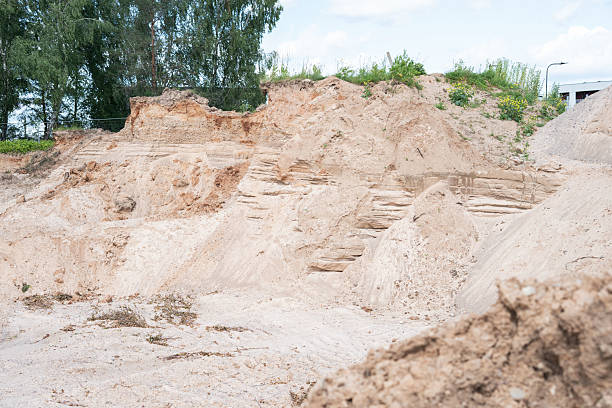 istock natural erosion reveals sandy layers in rugged terrain adjacent to verdant trees and under a clear sky, highlighting geological features and contrasting textures, organic, raw, undisturbed, scenic 2226256049