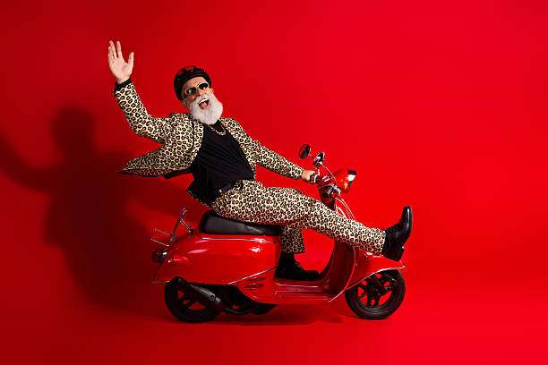 istock Charismatic Glamorous man in leopard print suit posing joyfully on red scooter against red backdrop 2226256313