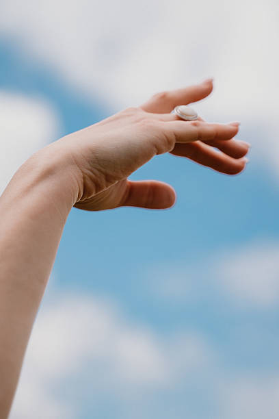istock Hand Reaching Up Towards Blue Sky and Clouds 2226257301