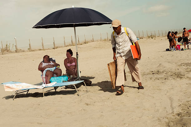 A summer day on a public beach. In the background are umbrellas, swimmers, and a blue sky with a few clouds. The image documents a typical seaside vacation moment in Italy, spontaneous and everyday.