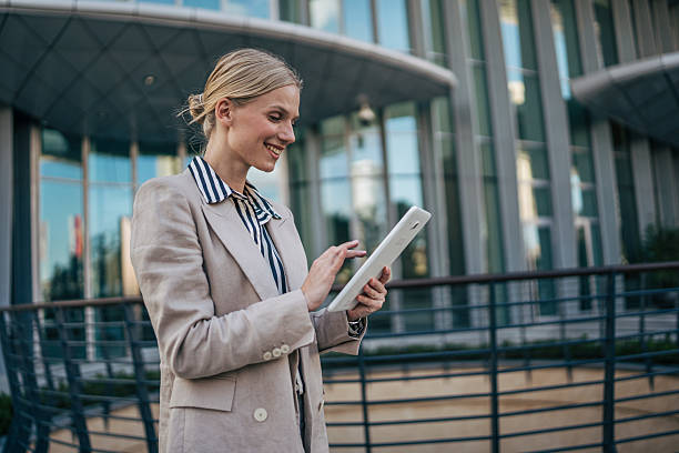 istock Smiling businesswoman using digital tablet outside modern office building 2226262722