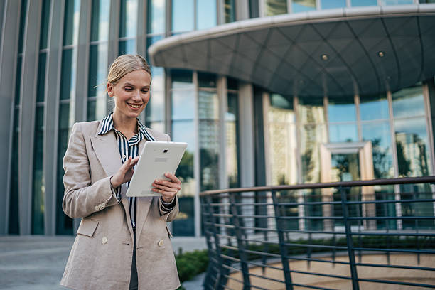 istock Smiling businesswoman using digital tablet outside office building 2226262728