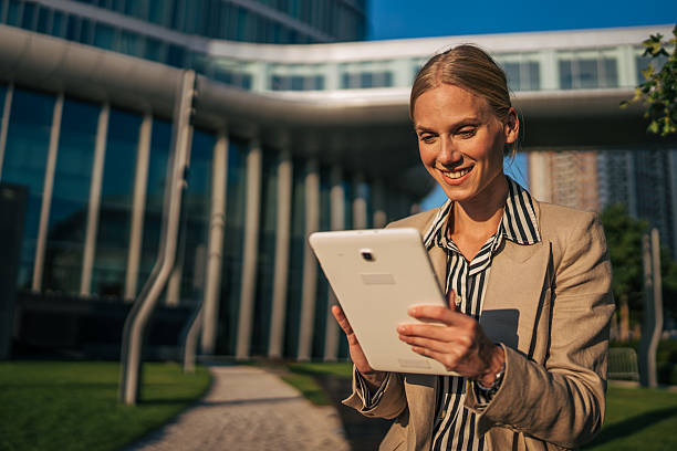 istock Smiling businesswoman using digital tablet outside modern office building 2226264362