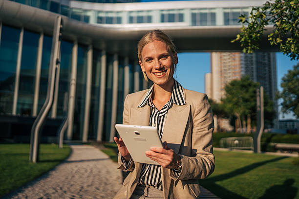 istock Smiling businesswoman using digital tablet outside office building 2226264363