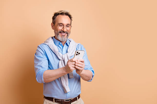 istock Confident middle-aged businessman using smartphone in casual attire against beige background 2226266155
