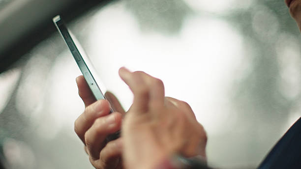 Asian mature woman using smartphone inside car.