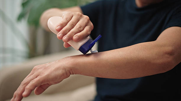 Asian mature woman applying arm cream at home.