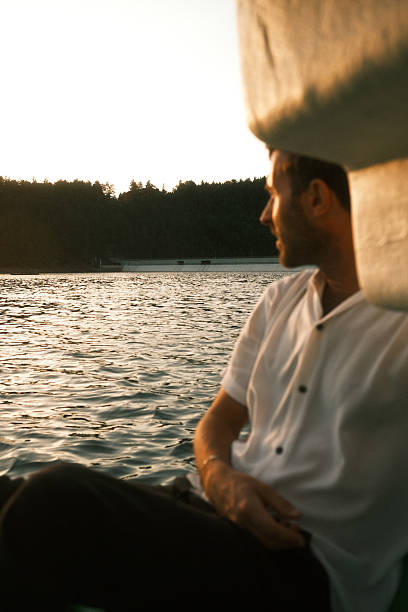 istock A man in a white shirt sits on a boat, looking at the water 2226273663