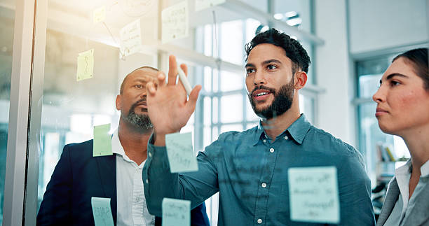 istock Teamwork, ideas and business people at glass with collaboration, sticky note and brainstorming in office. Strategy, problem solving and planning with moodboard for growth, development and discussion 2226276157