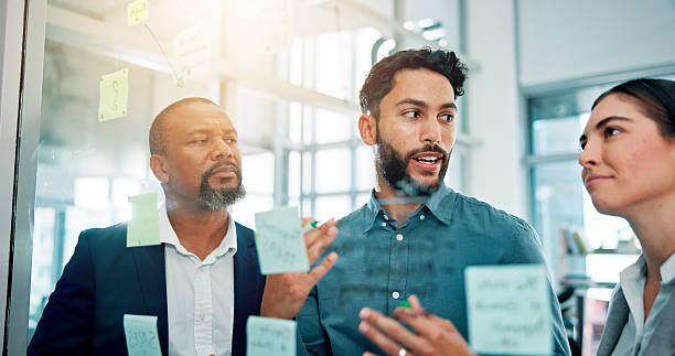 istock Collaboration, ideas and business people at glass with teamwork, sticky note and brainstorming in office. Strategy, problem solving and planning with moodboard for growth, development and discussion 2226276158