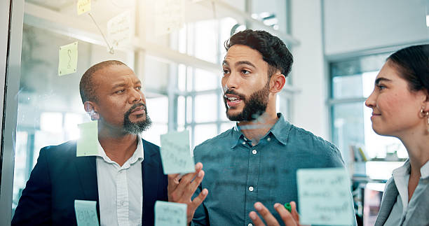istock Discussion, ideas and business people at glass with collaboration, sticky note and brainstorming in office. Strategy, problem solving and planning with moodboard for growth, development and teamwork 2226276164