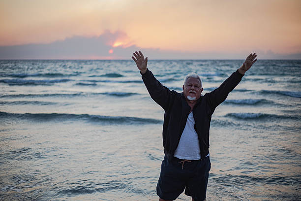 Overweight senior man exercising on sandy seashore, recreationally