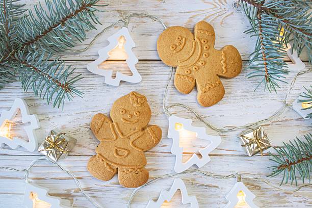 Christmas gingerbread cookies in the shape of a snowman on a white wooden background.