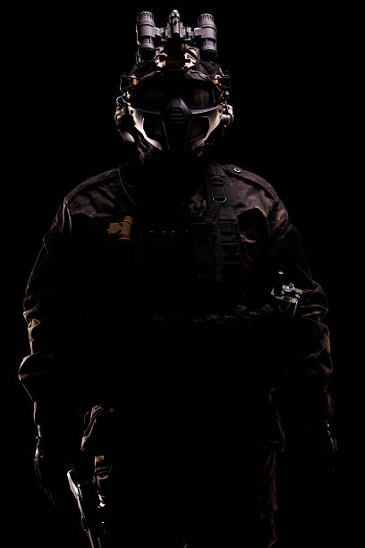 istock Silhouetted soldier in tactical gear holding a weapon on black background 2226286907