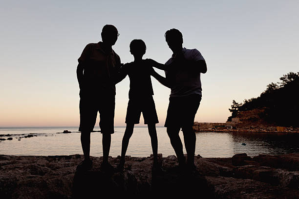 Silhouette of two happy children with their hands raised in worship. Outside. Sunset. Additional themes include praise and worship, kids, celebration, joy, peace, Christianity, religious, balance, wonder, awe, singing, happiness, togetherness, friends, friendship, love, faith, salvation, gratitude, attitude, hope, nature, and outdoors. Children are elementary aged and are unrecognizable. Caucasian models. 
