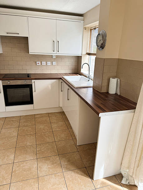 istock Image of bright modern rental kitchen, white gloss wall cabinets, wood-effect laminate worktop, durable tiled floor 2226297166