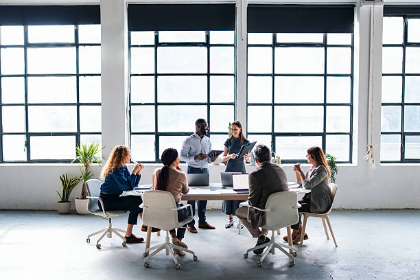 A diverse group of professionals collaborating in a modern office space, engaging in a productive team discussion to align project goals and ideas. Bright setting emphasizes team cooperation and innovative workplace spirit.