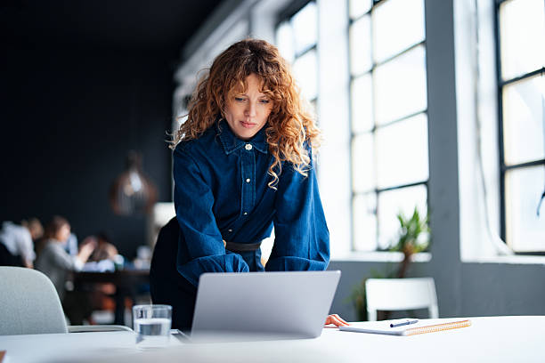 Confident Professional Woman Working on a Laptop in Modern Office Setting
