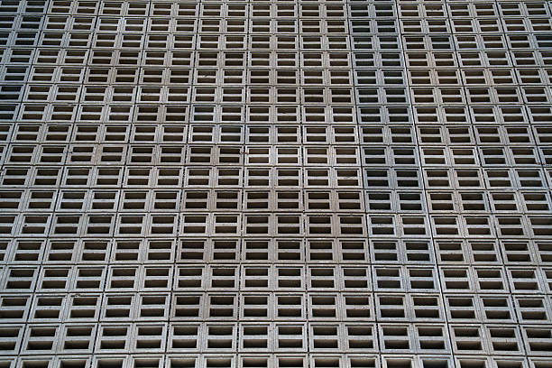 A close-up view of a vertical wall made from hollow concrete blocks arranged in a precise, repeating grid pattern for ventilation or architectural effect.