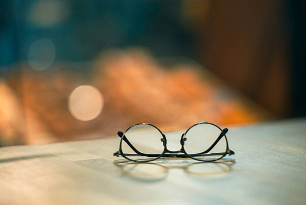 istock Round eyeglasses resting on a wooden surface with soft bokeh background, creating a calm and minimalist atmosphere indoors. 2226312152