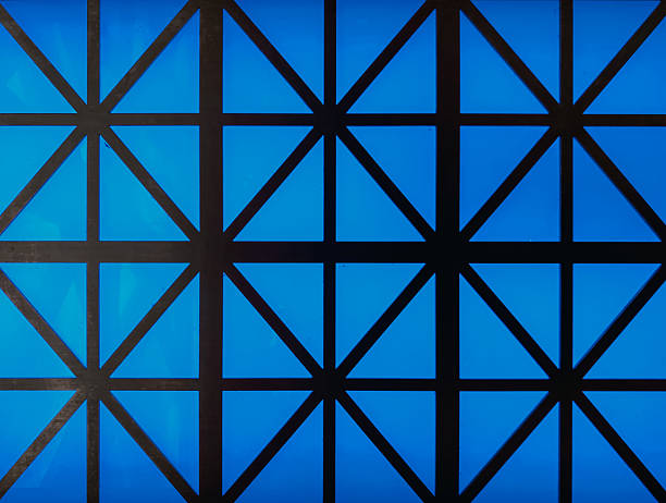 An intricate geometric structure featuring a lattice of steel beams forming a dome, illuminated with a soft blue light. Ideal for architecture, engineering, or modern design themes.