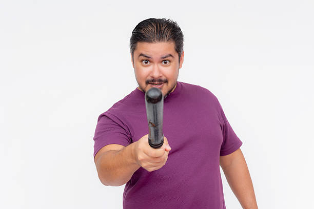 istock A stern man pointing at someone with a baton, giving a warning. Hostile person with a blunt weapon. Isolated on a white background. 2226314751