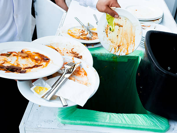 istock Male hands discarding food into trash bin. Food waste disposal. 2226318941