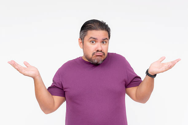 An indifferent man shrugs, claiming not to know what to do while smiling. Showing a bit sarcastic. Isolated on a white background.