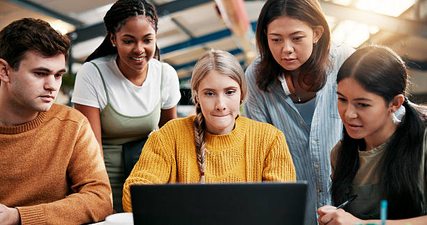 istock College, teamwork and students in library with laptop, project or research for assignment together. Knowledge, learning and people studying with education for exam, scholarship or university test 2226329303