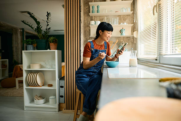 istock Woman enjoying breakfast and using smartphone in modern kitchen 2226333995