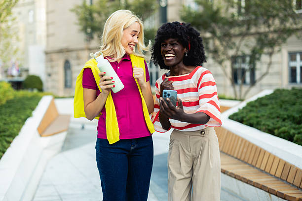 istock Two young women laughing while walking and using a smartphone in the city 2226336033