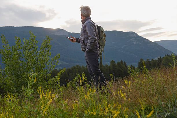 istock Mature man uses mobile phone in mountain meadow 2226336281