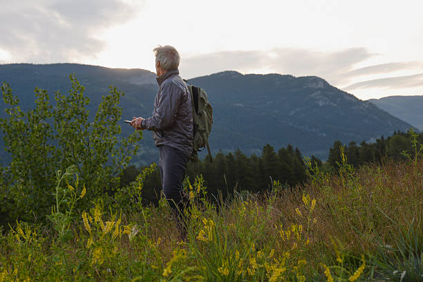 istock Mature man uses mobile phone in mountain meadow 2226336499