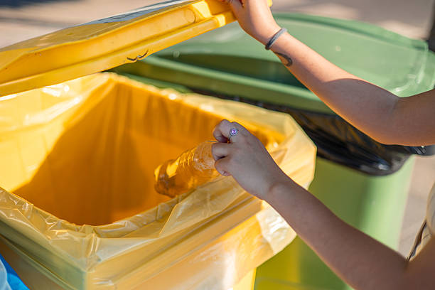 istock Woman throwing plastic bottle in yellow recycling bin, promoting environmental awareness 2226336907