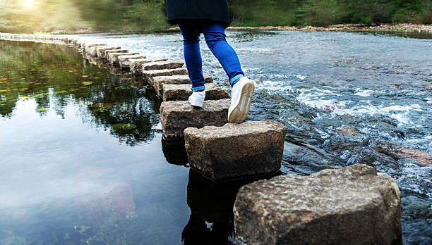 istock Woman crossing a river on stepping stones 2226337163