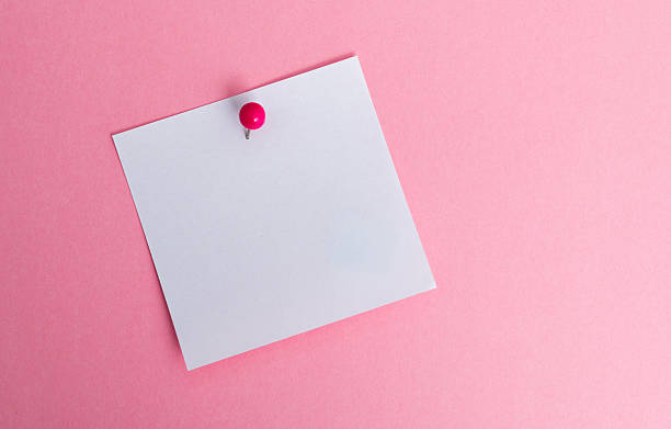 Blank white note paper with push pin isolated on pink background