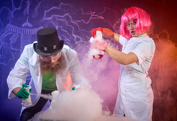 Amusing science, cheerful entertainment at a children's party. Man and woman in white lab coats doing chemical experiments. They are showing the flasks with steaming chemical substances and making funny face. Studio shooting on background with the chalk drawing on blackboard on chemical theme