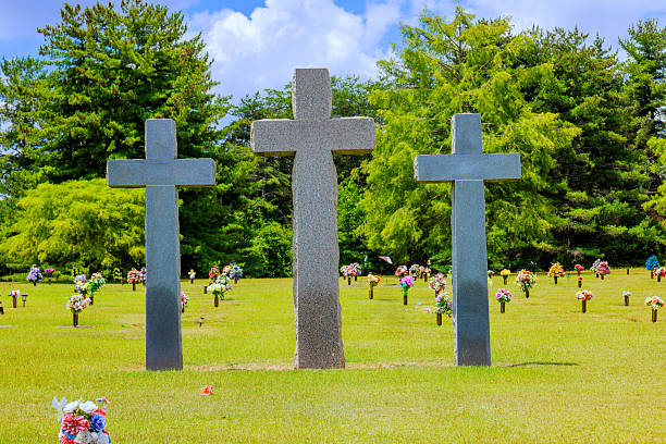 Three stone crosses standing in cemetery surrounded by flowers on sunny day in serene setting