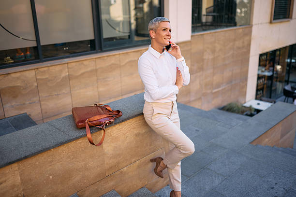 istock Businesswoman talking on the phone while leaning on a low wall 2226349289