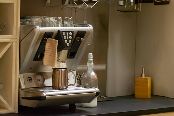 Wide view of a professional espresso coffee maker on countertop; milk jug, glasses, and syrup bottle create authentic bar setting.