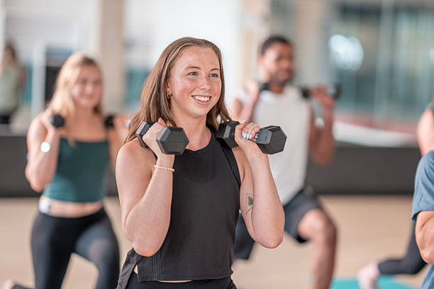 Group Strength Training Class with Participants Holding Dumbbells in a Gym Setting stock photo