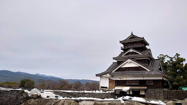 Kumamoto, Japan - Jan 26 2020: The impressive Kumamoto Castle main keep stands prominently against a cloudy sky, showcasing its unique architecture and ongoing restoration work after the earthquake