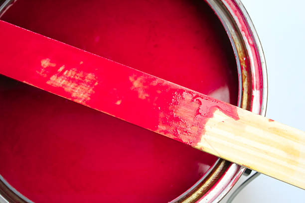 close-up of red paint or stain with a stir stick and copy space. home improvement or art design element or banner