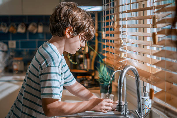 istock Young boy filling glass from kitchen water purifier 2226363183