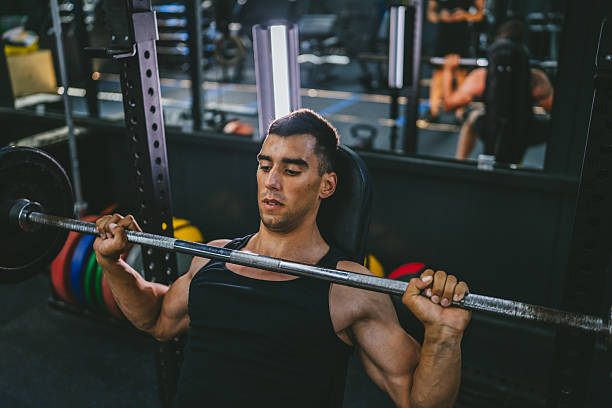 istock Handsome young athlete man doing bench press workout in gym 2226365998