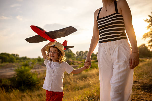 A mother and her son exploring the outdoors together.The boy carries a toy airplane.