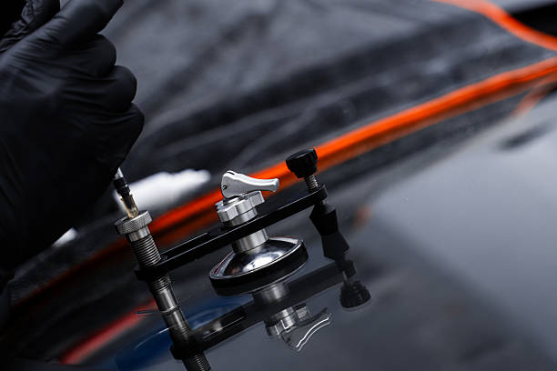 Resin repair on windshield using injector application to restore structural clarity. Windshield crack repair using resin injection. Technician using windshield injector tool to fix bullseye crack.