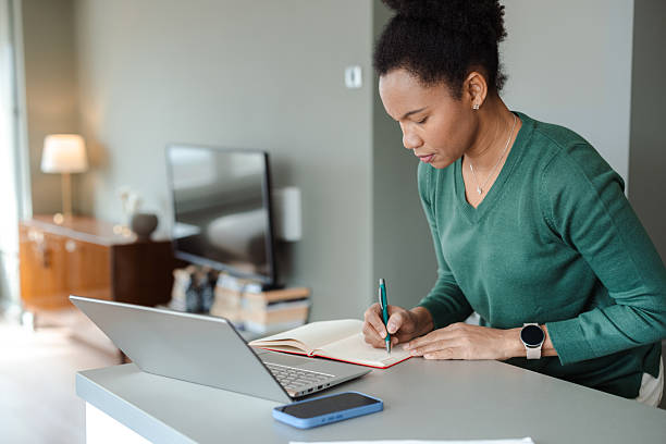 istock Focused woman writing notes while working on a laptop at home 2226376004