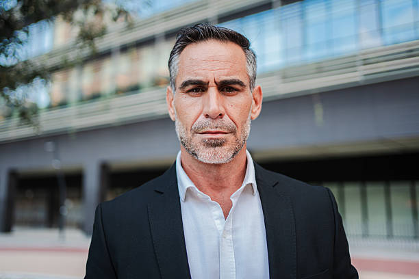 istock Distinguished Middle Aged Executive in Classic Black Suit Poses Confidently Outside Modern Corporate Building, Portraying Professional Mature Business Man with Authority and Seasoned Experience 2226378089